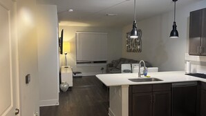 Une cuisine moderne avec des meubles en bois foncé, un plan de travail blanc et des luminaires suspendus.