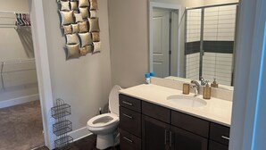 Une salle de bain moderne avec des toilettes, un lavabo, des meubles sombres et un grand miroir.