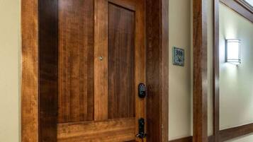 Una puerta de madera con cerradura electrónica, una placa con números y un accesorio de iluminación en la pared.