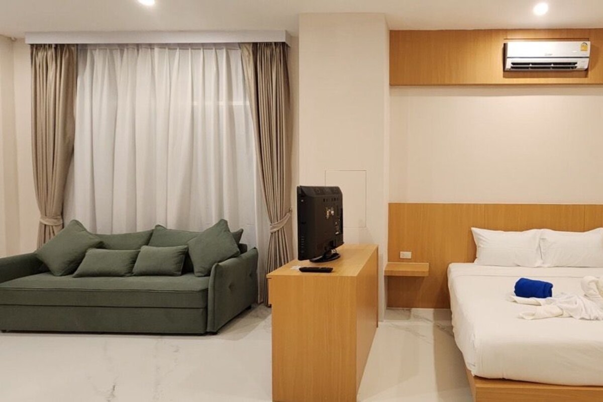 Ein Hotelzimmer mit Bett, Sofa, Fernseher und Klimaanlage.