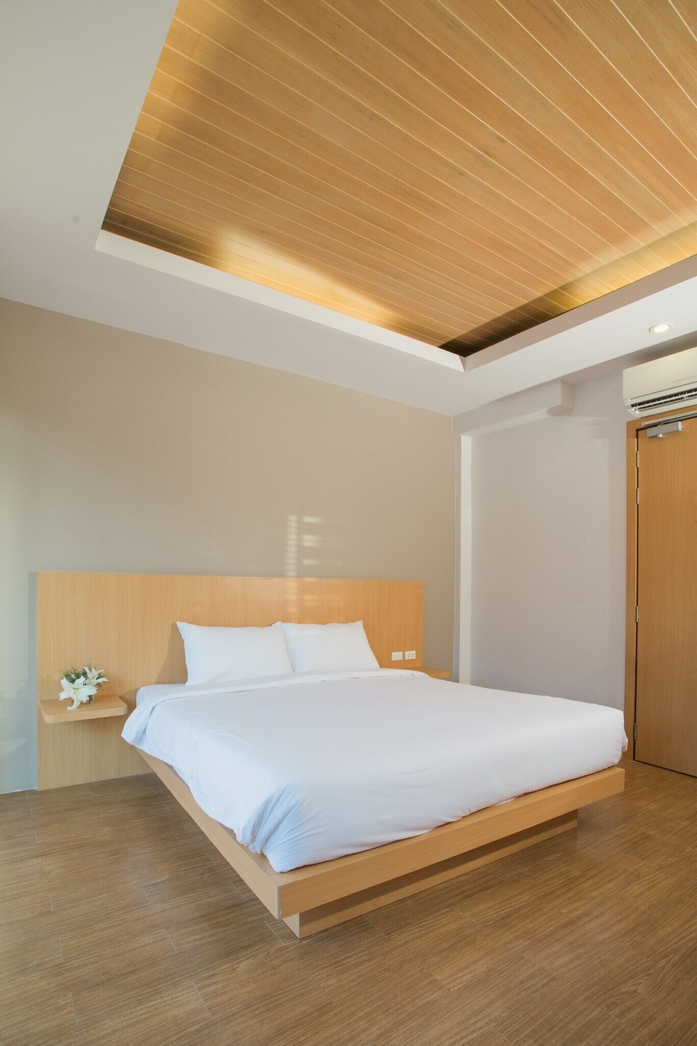 Un dormitorio moderno con estructura de cama de madera, mesita de noche y techo de madera.