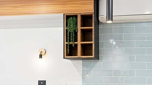 Un angle d'una habitació amb un armari de fusta, una planta penjant i una làmpada.