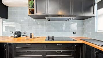 A kitchen with black cabinets, a wooden countertop, and a built-in stove.