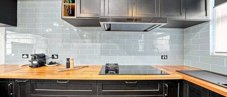 A kitchen with black cabinets, a wooden countertop, and a built-in stove.