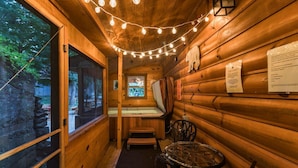 A cozy cabin interior with wooden walls, a bench, a table, and string lights. - Cozy Bear Cabin - Log Cabin Soul, Nashville Heart (Nashville)