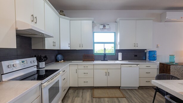 A modern kitchen with white cabinets, a built-in oven, and a window providing natural light. - Oceanfront 3BR Condo, Pool, Direct Beach Access (Cole Bay)