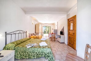 A bedroom with a bed, a desk, a chair, a television, and a wooden door.
