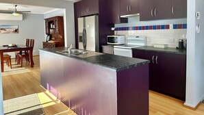 A modern kitchen with dark cabinets, a central island with a sink, a microwave, and a stove. - Among the Gums, Armagh, Clare Valley (Armagh)