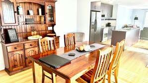 A modern kitchen with wooden cabinetry, a dining table with chairs, and a built-in island with a sink. - Among the Gums, Armagh, Clare Valley (Armagh)