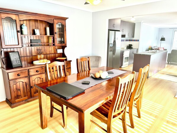 Une cuisine moderne avec des meubles en bois, une table à manger avec des chaises et un îlot central intégré doté d’un évier.