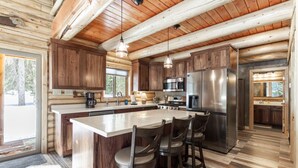 Una cocina amplia con una isla grande, armarios de madera, electrodomésticos de acero inoxidable y un suelo con estampado de espiga.