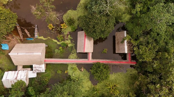 Luchtbeeld van een rivierengebied met houten constructies, een brug en weelderige begroeiing.