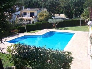 Una piscina rectangular con superficie de agua azul cristalina, rodeada por una solana pavimentada.