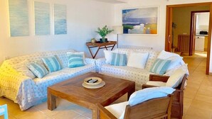A living room with a sofa set, a coffee table, and a painting on the wall.