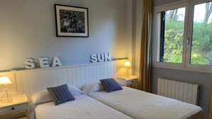 A hotel room with two beds, a framed picture on the wall, and a window with curtains.