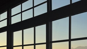 A view through a window with multiple panes, revealing a distant landscape with mountains and a hazy sky. - Pax & Opis Luxury Villa (Mussoorie)