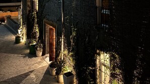 A stone building with a wooden door and windows, surrounded by potted plants and a stone pathway. - Pax & Opis Luxury Villa (Mussoorie)