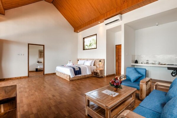 A spacious room with a large bed, a blue sofa, and a wooden coffee table. - Seraya Cove Estate by Manara (Karangasem)