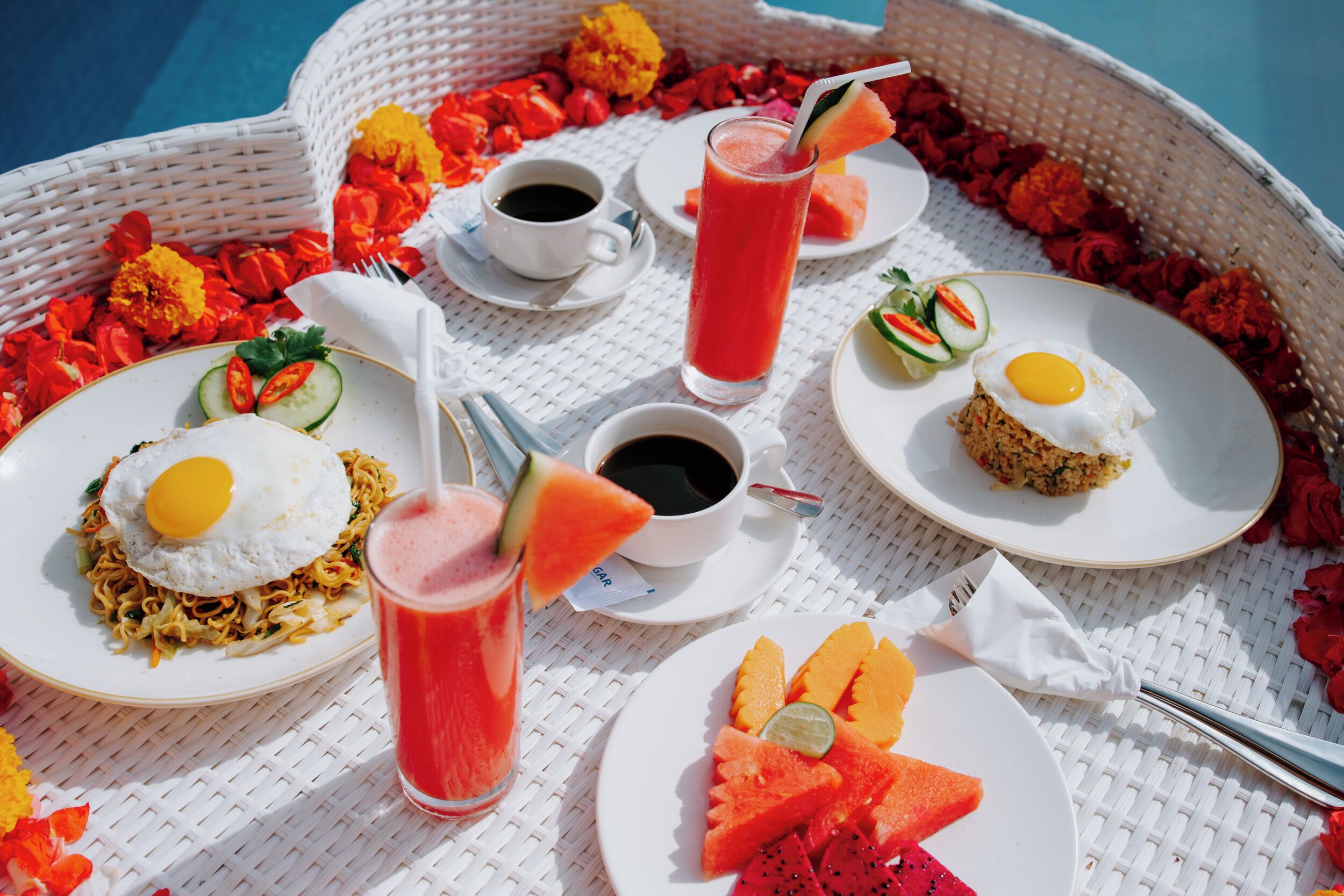 Bandeja de desayuno con platos de comida, bebidas y una cesta de mimbre.
