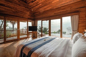 Une chambre avec un grand lit, un plafond en bois et un téléviseur posé sur un meuble en bois.