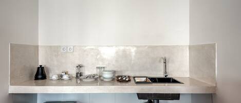 A kitchen with a countertop, sink, and a coffee maker.