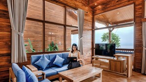Ein Holzinterieur mit einer Couch, einem Couchtisch, einem Fernseher und großen Fenstern.