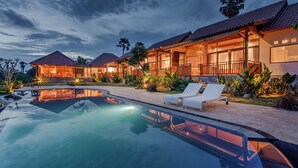 A resort with a swimming pool, lounge chairs, and a large house with a tiled roof. - Seraya Cove Estate by Manara (Karangasem)