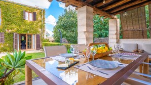 Un'area pranzo con un tavolo in vetro apparecchiato per due, circondata da una pergola in legno.