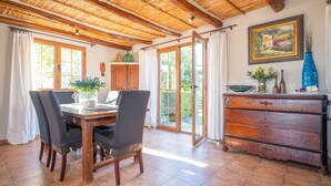 Zona pranzo con tavolo e sedie in legno, un armadietto in legno e vista sull'esterno tramite una porta in vetro.