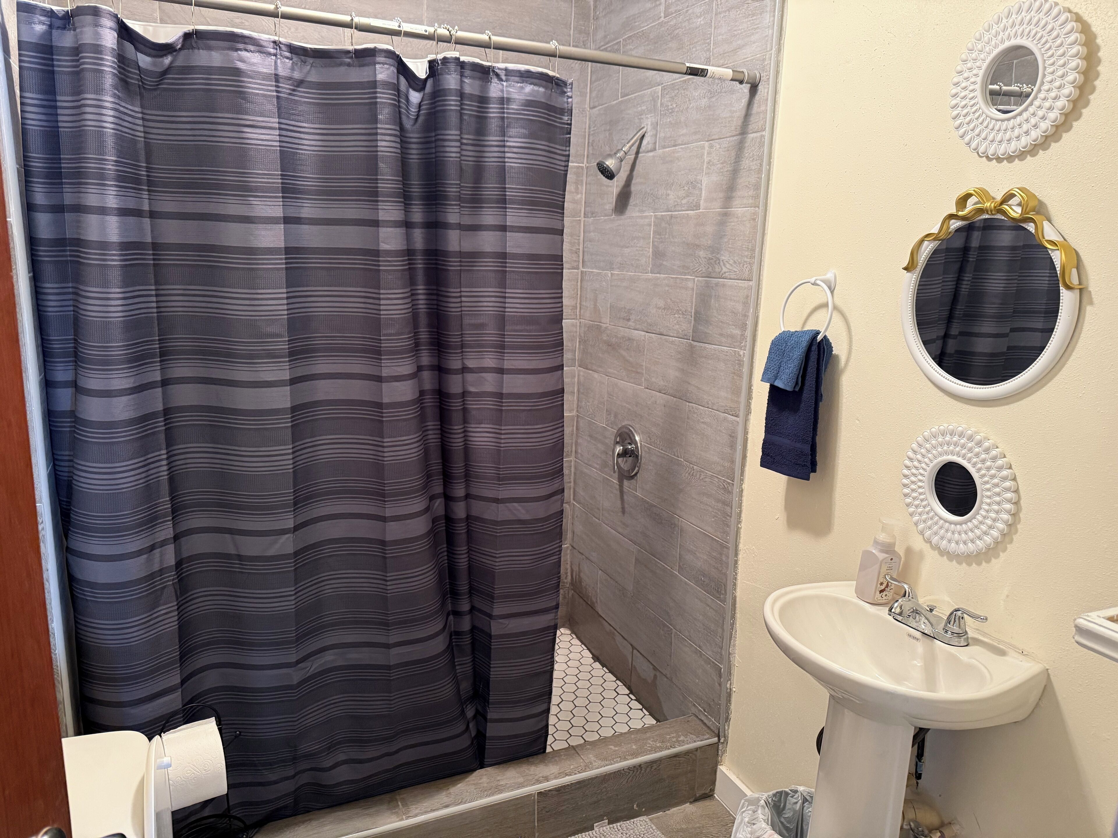 Une salle de bain avec une douche, un lavabo et des miroirs décoratifs.