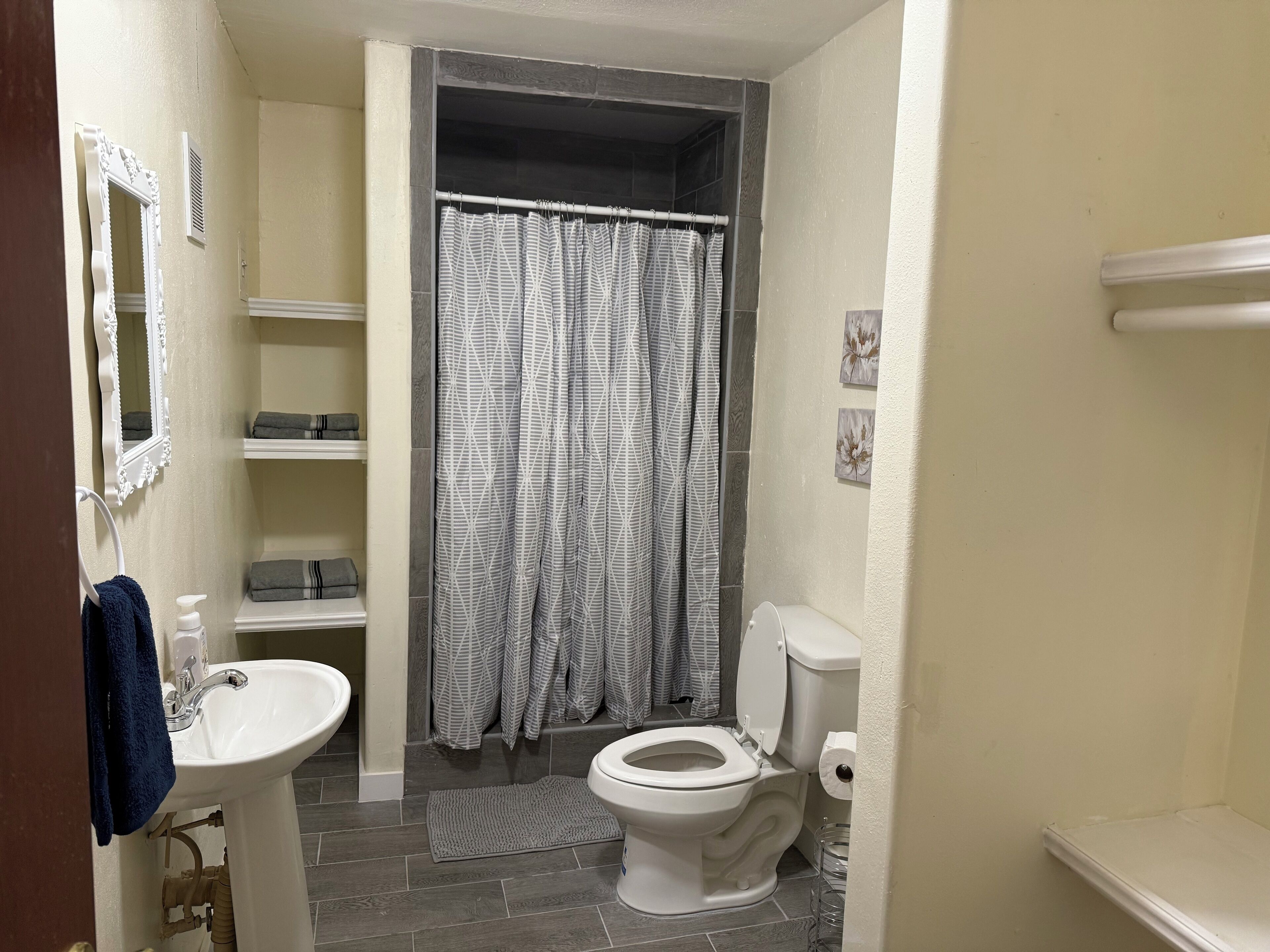 A bathroom with a white sink, a toilet, a shower curtain, and a mirror.