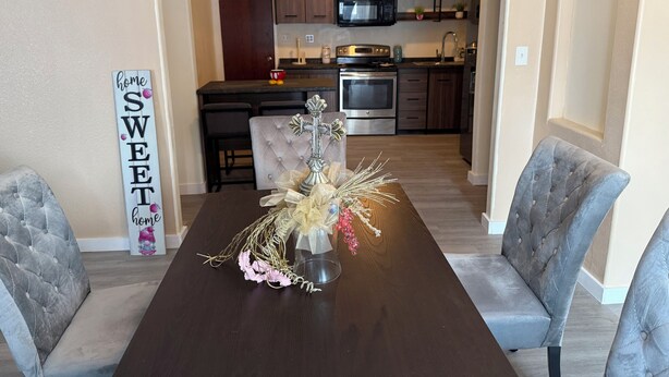 A dining area with a dark wooden table, grey upholstered chairs, and a decorative centerpiece. - REMODELED Stellar Yellow House w/mini cine, near Plaza Mall & Downtown McAllen (McAllen)