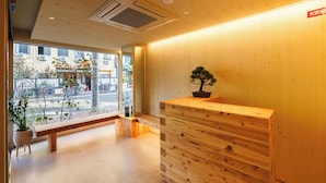 A reception area with a wooden desk, a potted plant, and a bench. - 2Z - DOYANEN HOTELS (Osaka)