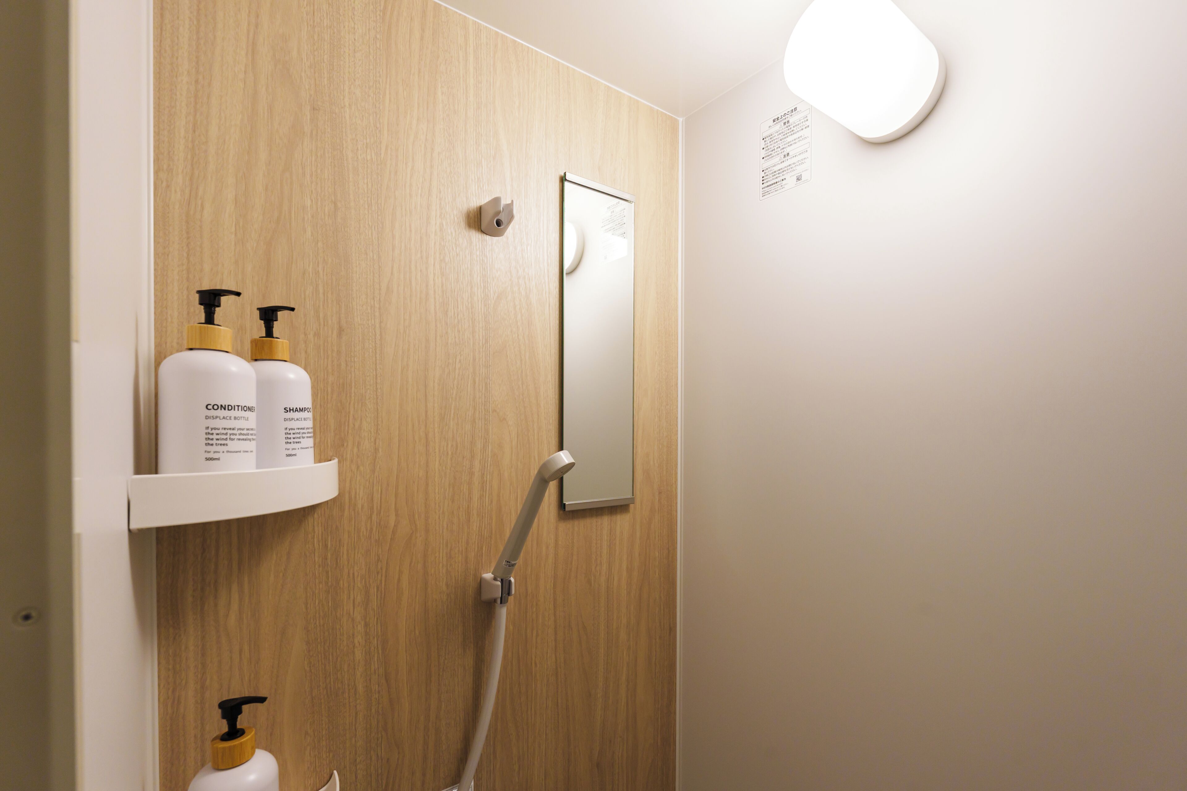 A bathroom with a wooden panel wall, a mirror, and two white bottles on a shelf.