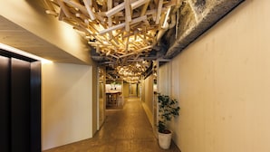 A hallway with wooden beams, a potted plant, and a table with chairs. - 2Z - DOYANEN HOTELS (Osaka)