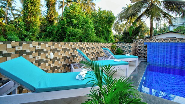 A poolside area with lounge chairs and a tiled wall. - Hotel Eyokar Goa (Candolim)
