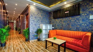 A hotel lobby with a wooden parquet floor, a red sofa, and potted plants. - Hotel Eyokar Goa (Candolim)