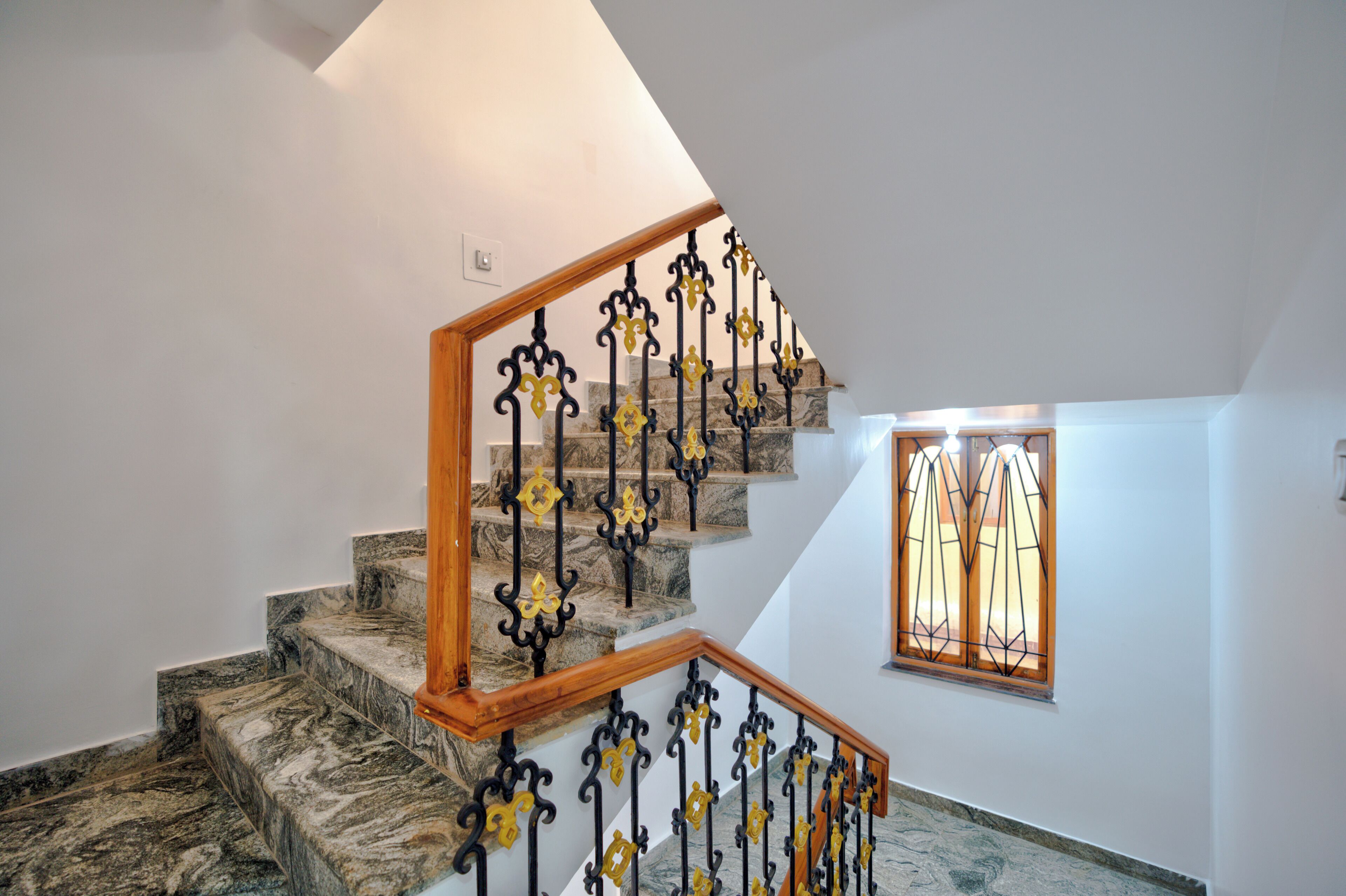 Una escalera con escalones de mármol y barandillas de hierro forjado en amarillo y negro.