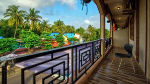 A balcony with a view of palm trees and colorful buildings. - Hotel Eyokar Goa (Candolim)