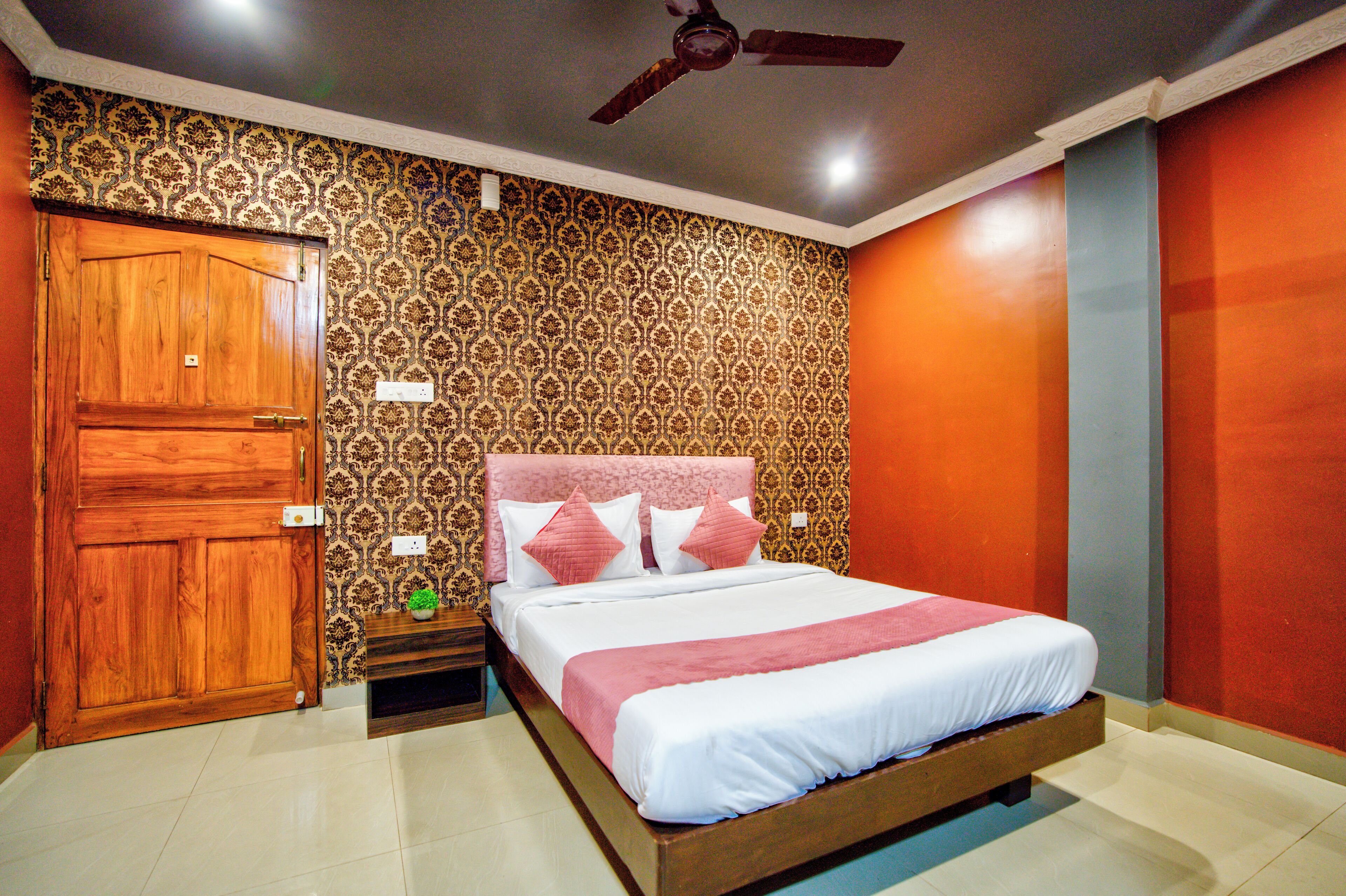 A bedroom with a wooden bed, patterned wallpaper, a ceiling fan, and a wooden door.