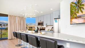 Una cocina moderna con una isla grande, taburetes de bar y vistas al océano.