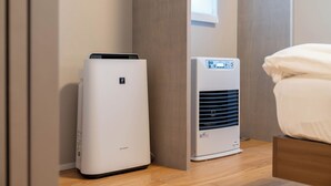 Zwei Klimaanlagen in einem Zimmer mit Holzboden und einem Bett mit weißer Bettwäsche.