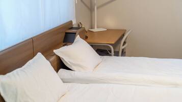 A hotel room with a bed, bedside table, lamp, and a chair.