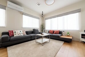 Una sala de estar moderna con un sofá gris, una mesa de centro blanca y una mesita auxiliar con una lámpara.