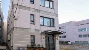 Ein mehrstöckiges Gebäude mit schlichter Fassade, großen Fenstern und einem überdachten Eingang.