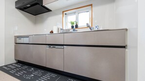 Eine moderne Küche mit eingebautem Geschirrspüler, einem Fenster über der Spüle und einer schwarzen Matte mit Kaffeemotiven.