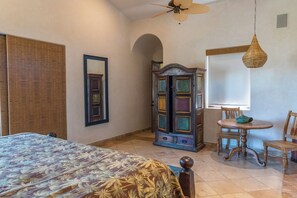 A bedroom with a bed, a wardrobe, a dining table with chairs, and a ceiling fan. - Stunning 4BR Villa w/ Ocean Views, Infinity Pool, Hot Tub & Butler Service (Cabo San Lucas)