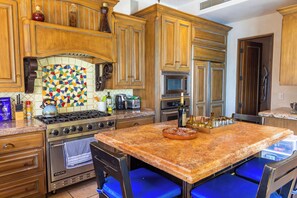 A kitchen with wooden cabinets, a tiled backsplash, a stove, and a microwave. - Stunning 4BR Villa w/ Ocean Views, Infinity Pool, Hot Tub & Butler Service (Cabo San Lucas)