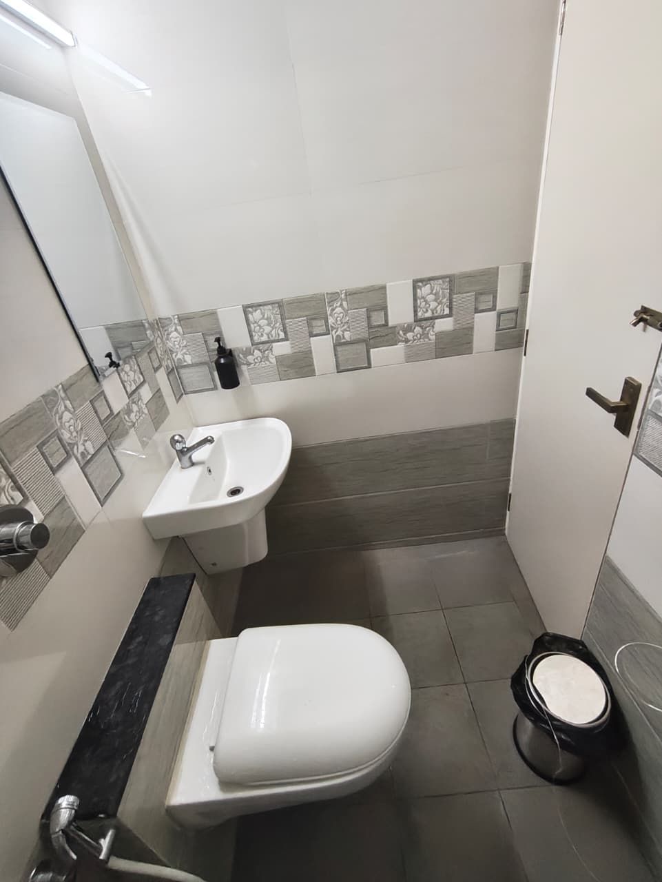 A small bathroom with a toilet, sink, and shower.