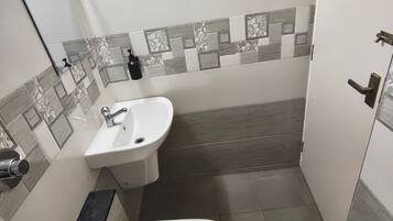 Baño pequeño con inodoro, lavabo y ducha.